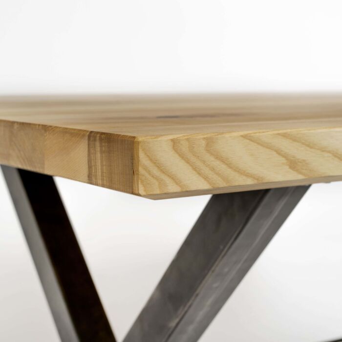Das Detailbild zeigt eine Tischecke vom Massivholz-Tisch X-Gestell metall schwarz. Auch die Verarbeitung der Tischplatte mit ihren abgeschrägten Kanten ist zu erkennen.